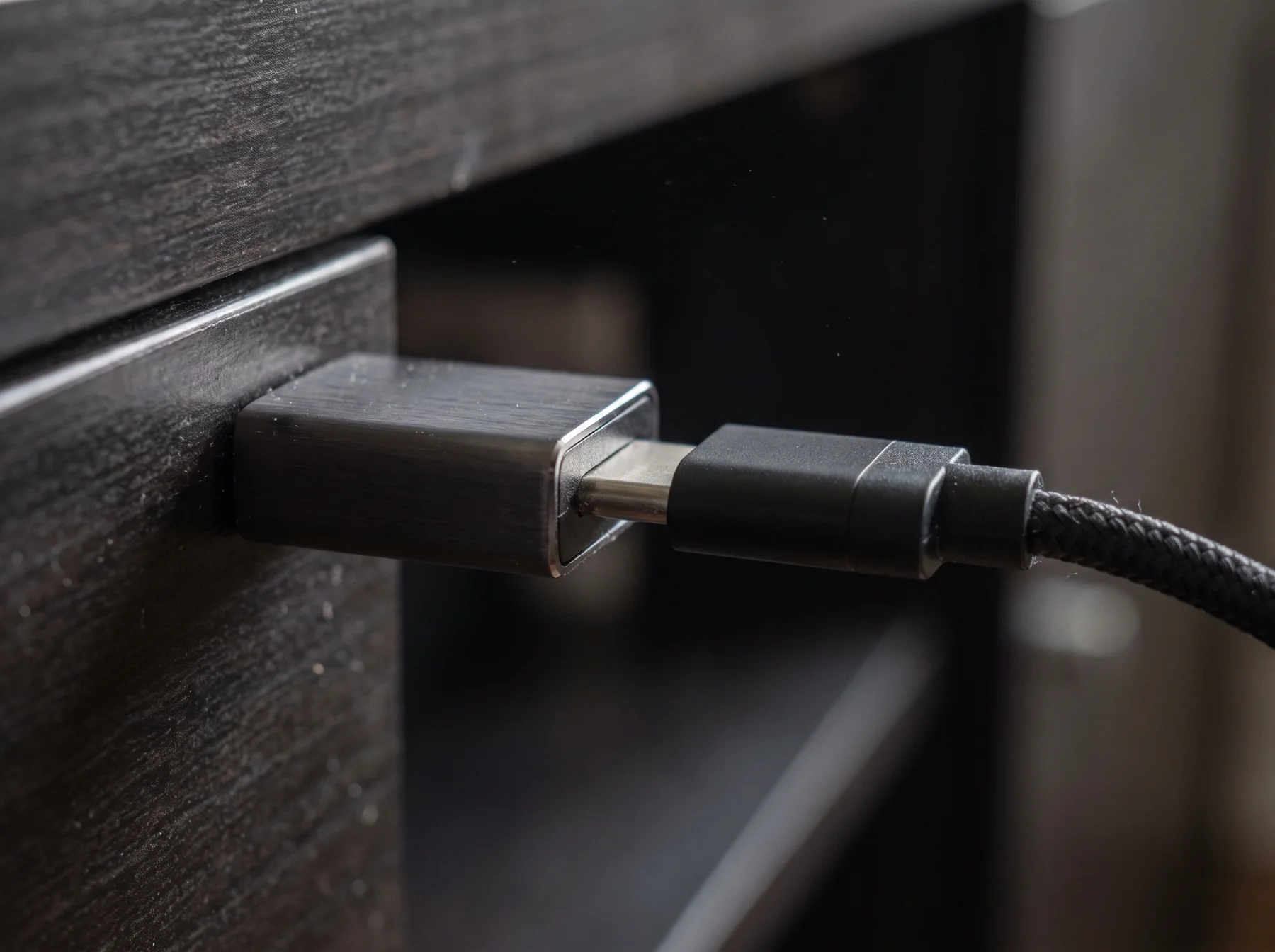 Close detail of HDMI and power connectors on a dark media cabinet
